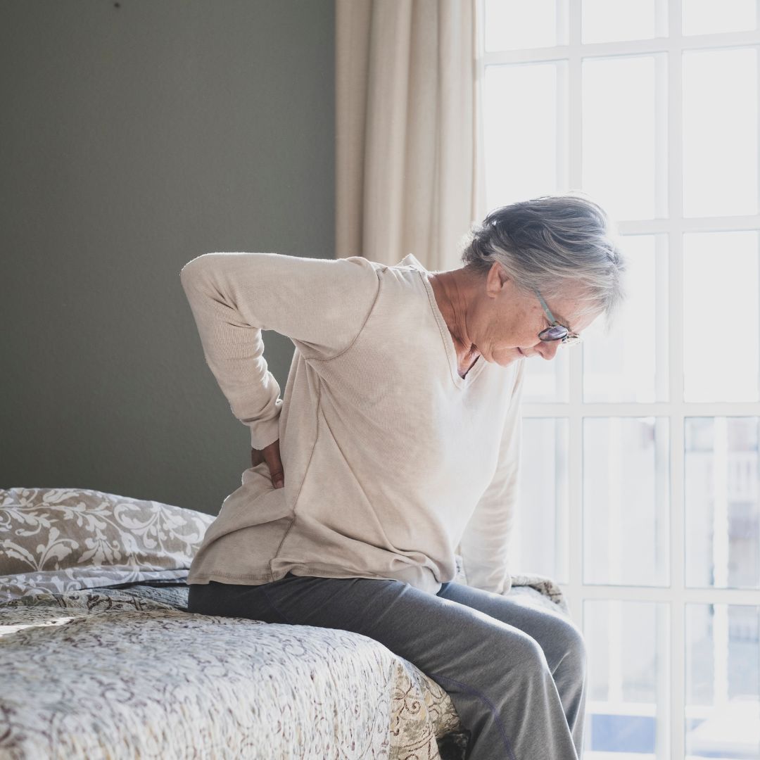 Woman with a back ache sitting on bed